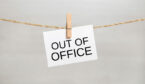 A sign saying out of office is pegged onto a string