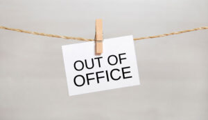 A sign saying out of office is pegged onto a string
