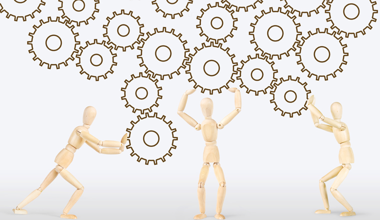 3 wooden figures pushing a group of cogs