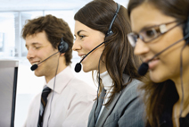 Three young customer service operators sitting in a row and talking on headset. Selective focus on women in middle. Isolated on white background.