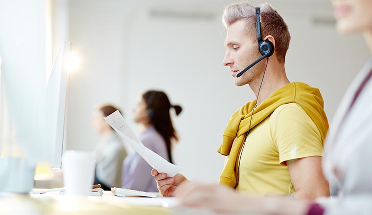 Young businessman working in call centre. He is sitting at the table in headset