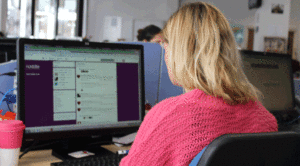 A back view of a blond haired lady wearing a pink jumper. 