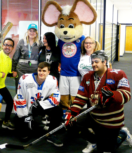 Members of the team pose with a mouse mascot and dress up as hockey players