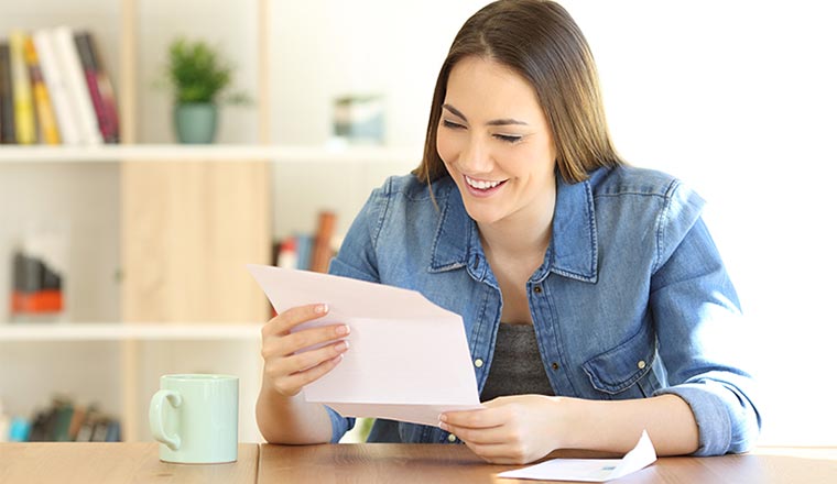 Happy woman reading a letter on a table at home