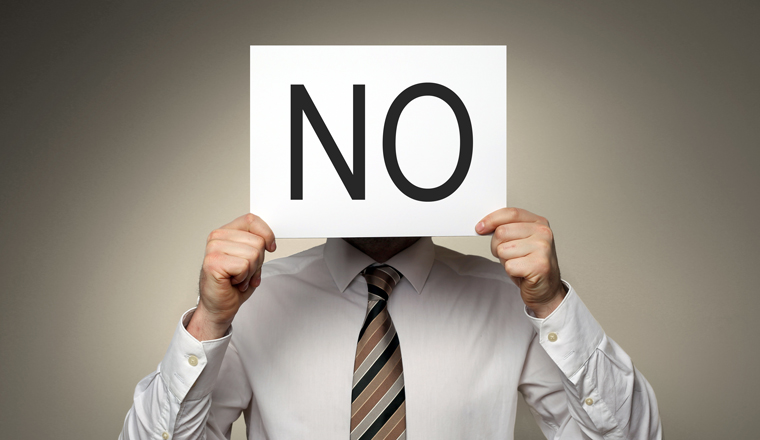 A man holds a sign saying no over his face