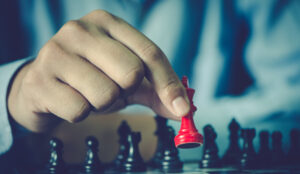 Man moves a red chess piece across chess board