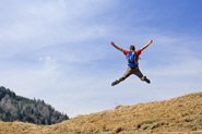 A person jumps into the air on the side of a hill