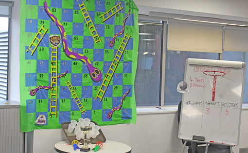 A snakes and ladders board is hung on the wall of a call centre