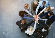A team huddle with everyone putting their hands in the middle of the group.