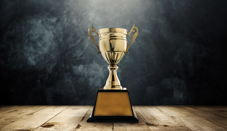 Golden trophy on a wooden desk with a dark smoky background