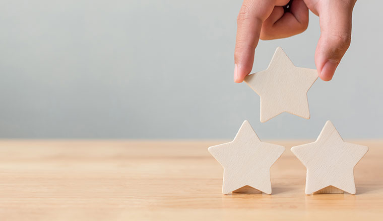 Hand putting wooden five star shape on table.