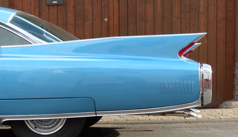 A blue vintage car bumper against a wooden panelled background