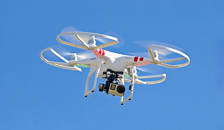 white drone hovering in blue sky