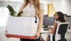 Fired female employee holding box of belongings in an office