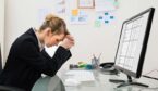 Stressed Young Businesswoman Sitting At Desk In Office