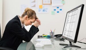 Stressed Young Businesswoman Sitting At Desk In Office