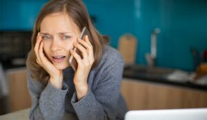 Closeup portrait of worried young woman talking on smartphone in kitchen