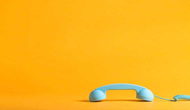 Vintage style blue telephone handset on a yellow background