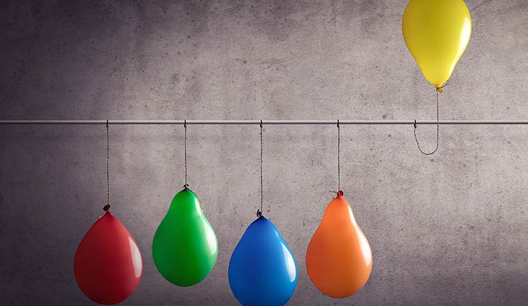 Four balloons in a row, with a yellow one raised off the ground