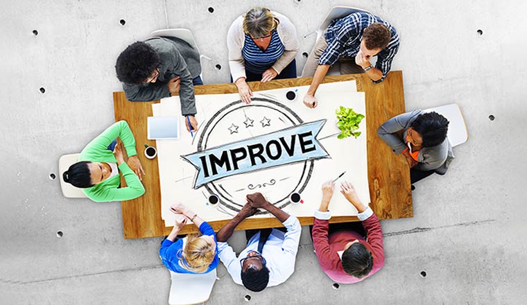 A team sit around a table with improve written on it