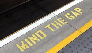A mind the gap sign painted on the floor of a train station