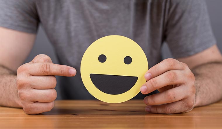 A man holds a smiley face cut out