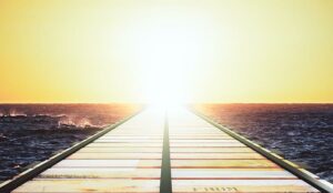 A picture of a boardwalk leading to the sunset