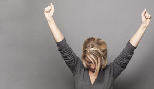 A photo of successful young woman winning with both arms up