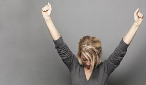 A photo of successful young woman winning with both arms up