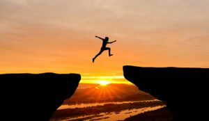 A man jumps from one rock to another, over a very large gap