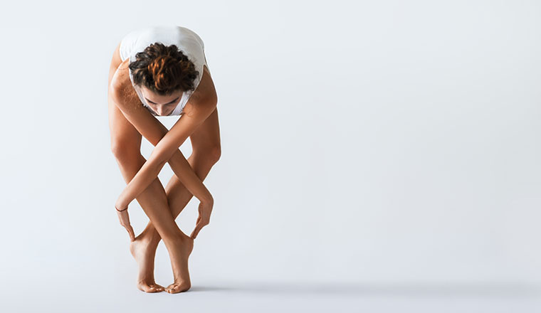 Young dancer posing on a studio background with arms interwoven