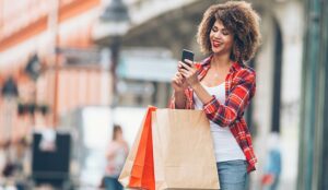 Young woman at the street with shopping bags using mobile phone