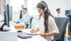 A white woman with long brown hair wears a headset