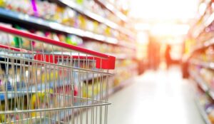 Supermarket interior, empty red shopping cart.