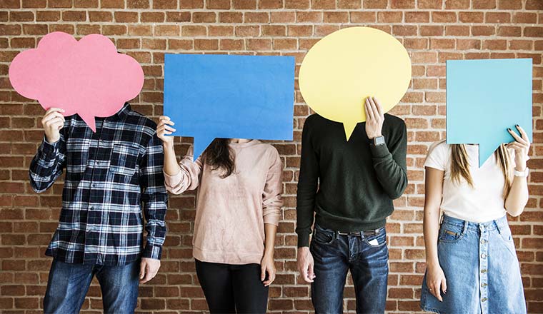 A photo of four people holding speech bubbles over their faces