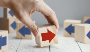 A red arrow on a wooden block faces a different way to blue arrows on other blocks