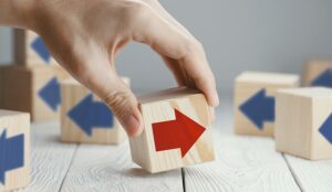 A red arrow on a wooden block faces a different way to blue arrows on other blocks