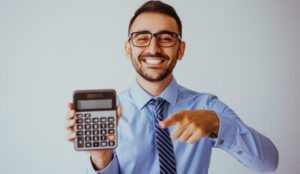 A happy looking man points towards his calculator