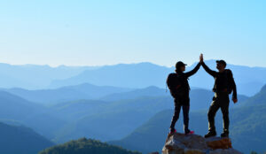 Two people on top of a rock high five