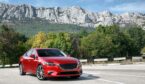 A photo of a Red car standing on the road near mountains at daytime