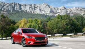 A photo of a Red car standing on the road near mountains at daytime