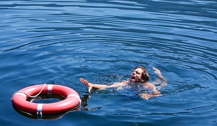 A photo of a man struggling for a life buoy in the water