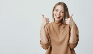 female customer with broad smile, looking at the camera with happy expression, showing thumbs-up with both hands,