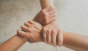 A photo of three people joining hands together