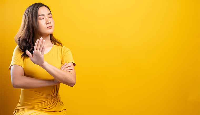 Woman making stop sign with hand on isolated yellow background