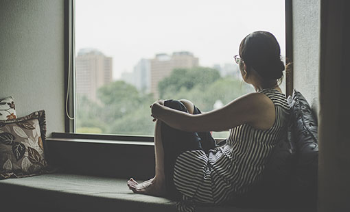 A photo of a woman staring out of the window while thinking