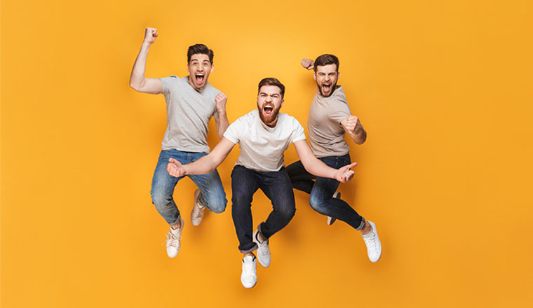 A photo of three happy men jumping together