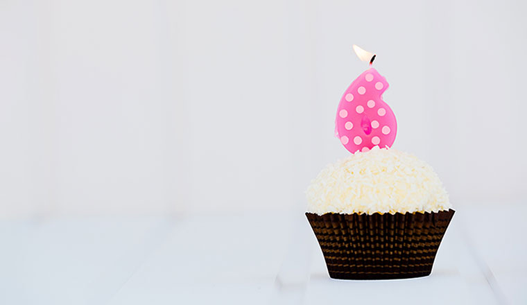 A photo of a cupcake with a candle shaped like a six