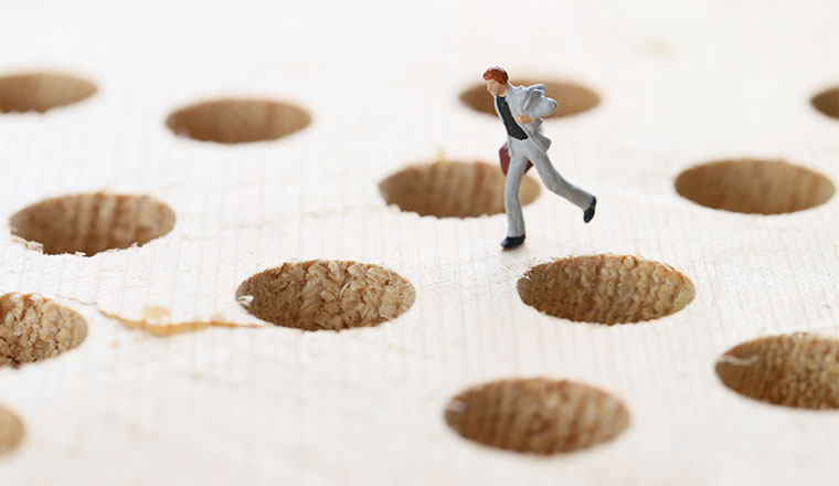 A photo of a figurine safely standing away from some holes in the ground