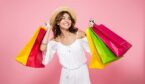 A photo of a joyful smiling girl holding lots of colorful shopping bags and looking away isolated over pink background